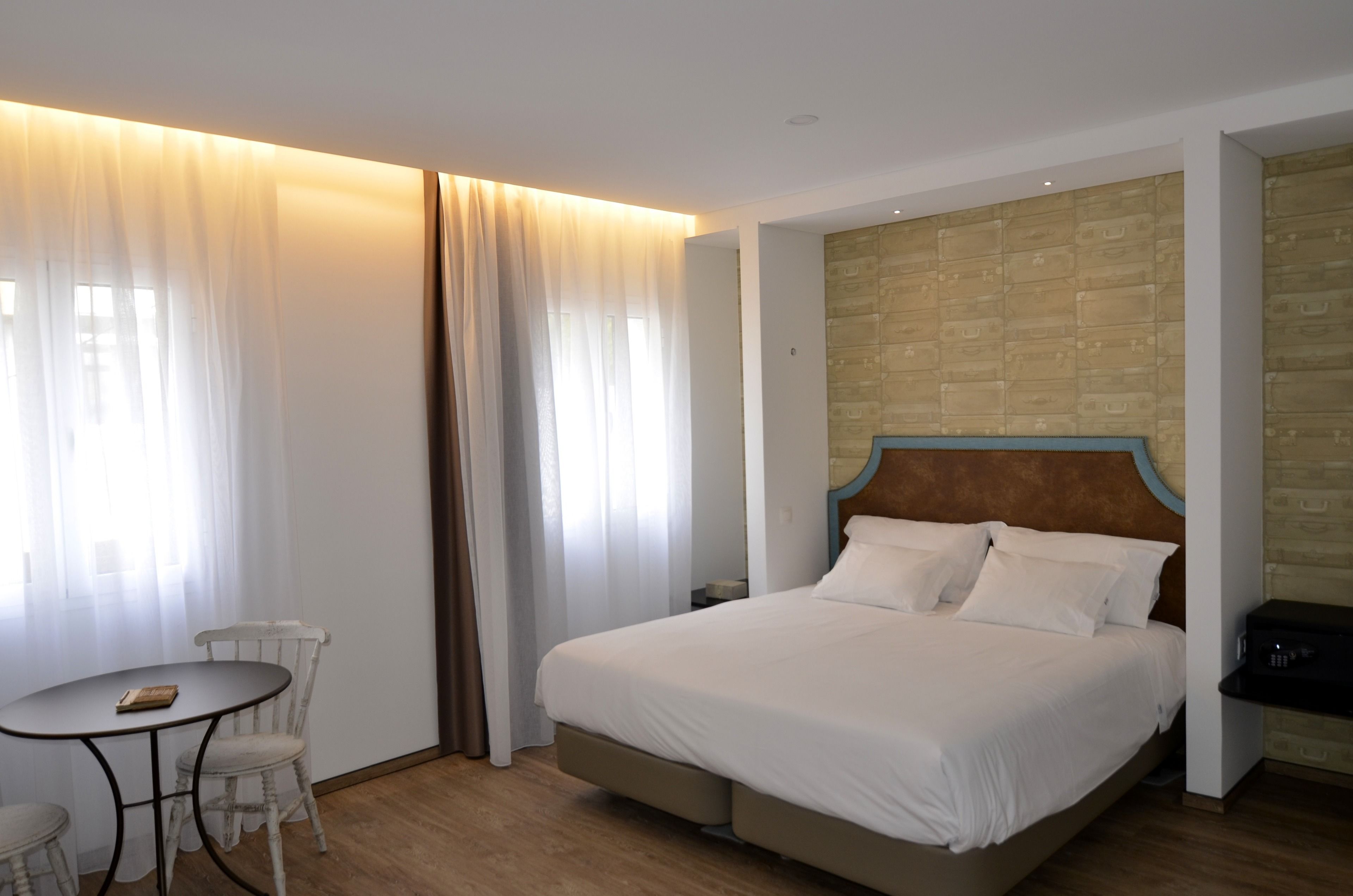 Ein Hotelzimmer mit Bett, einem kleinen Tisch mit Stühlen und einer Wand mit Struktur.