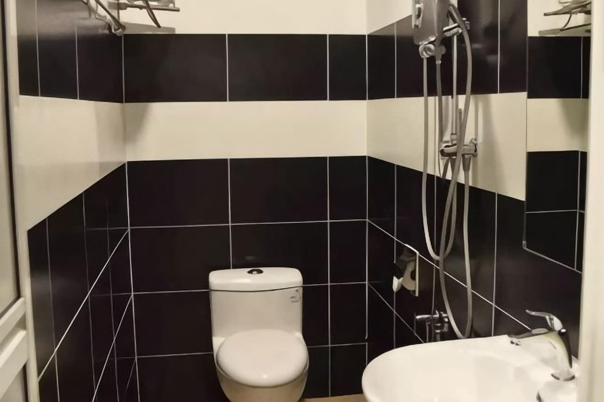 A bathroom with black and white tiles, a toilet, a sink, and a shower.