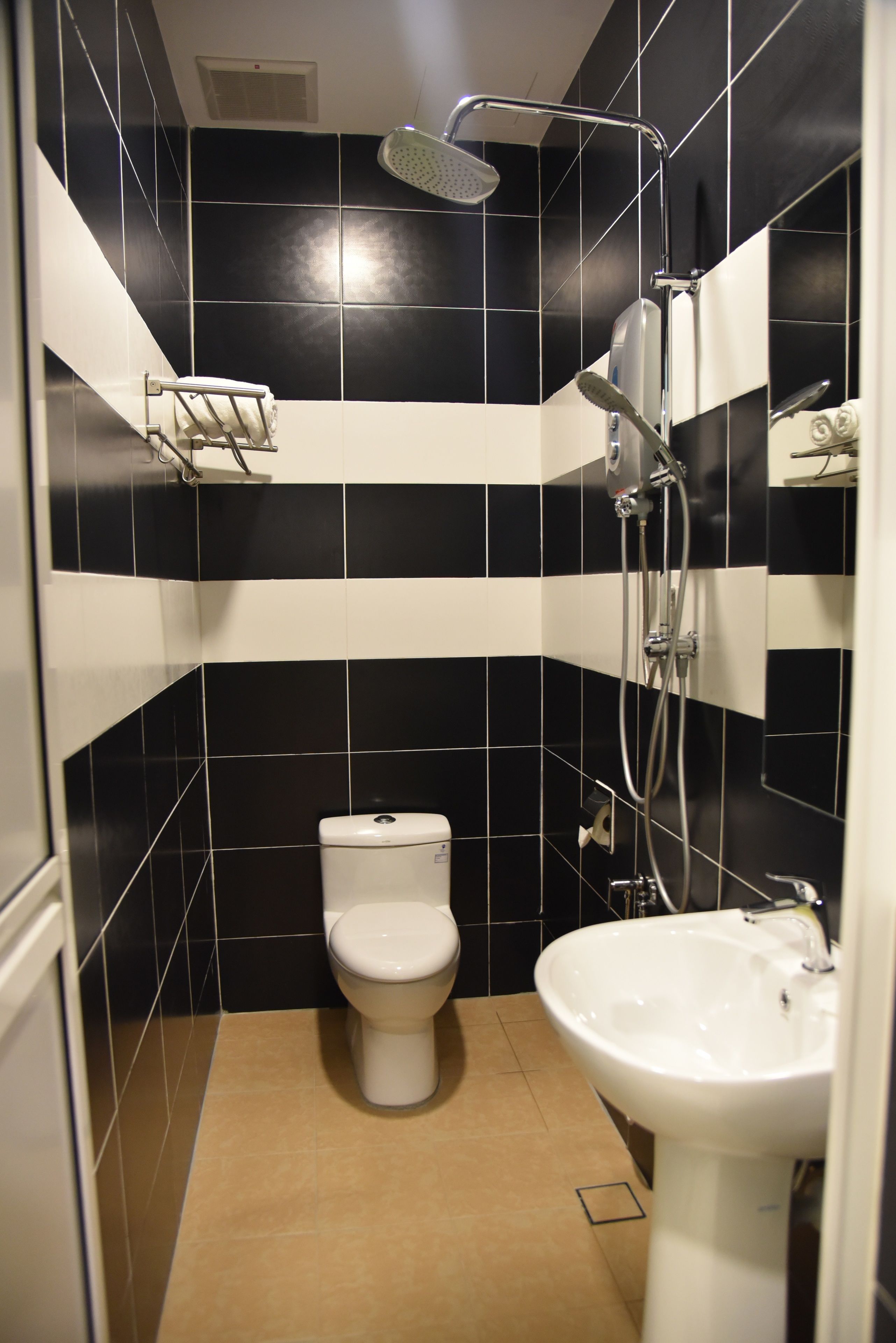 Een badkamer met zwart-wit tegels, een toilet, een wastafel en een douche.
