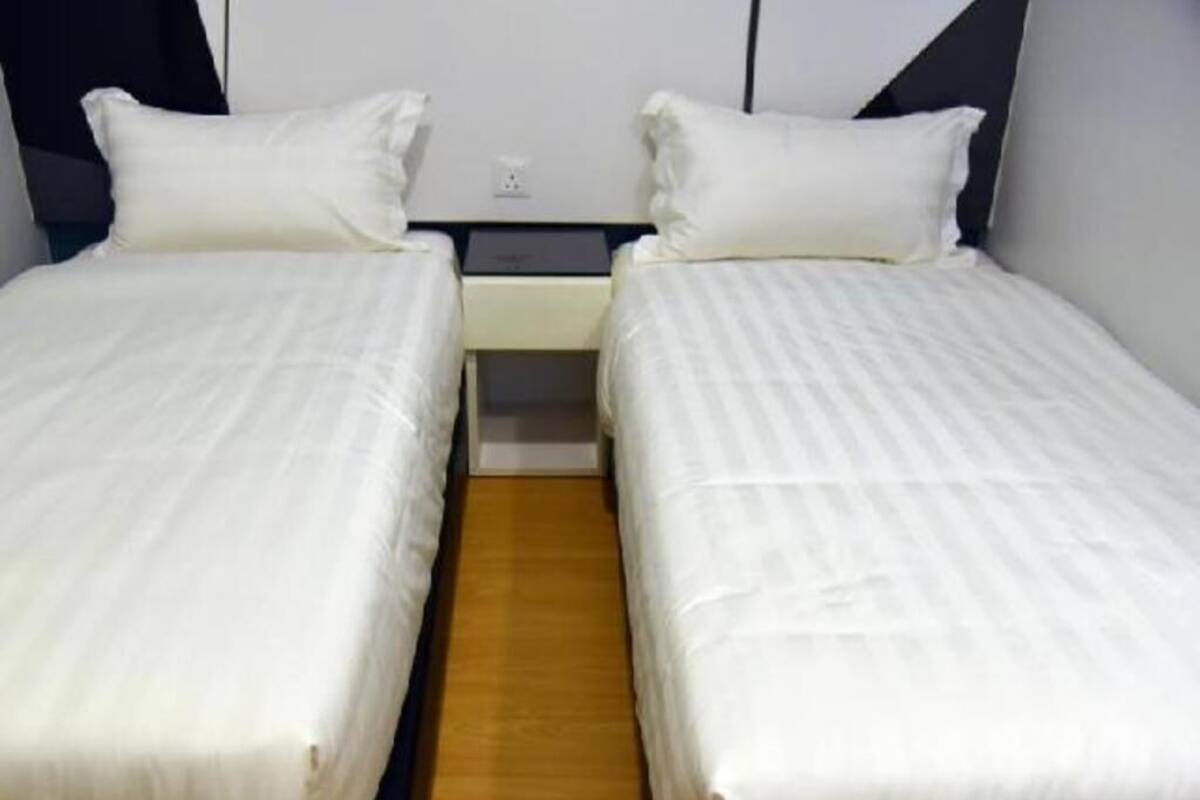Ein Doppelbett mit weißer Bettwäsche, Holzboden und ein Nachttisch mit Lampe.