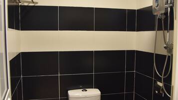 A bathroom with black and white tiles, a white toilet, a showerhead, and a towel rack.