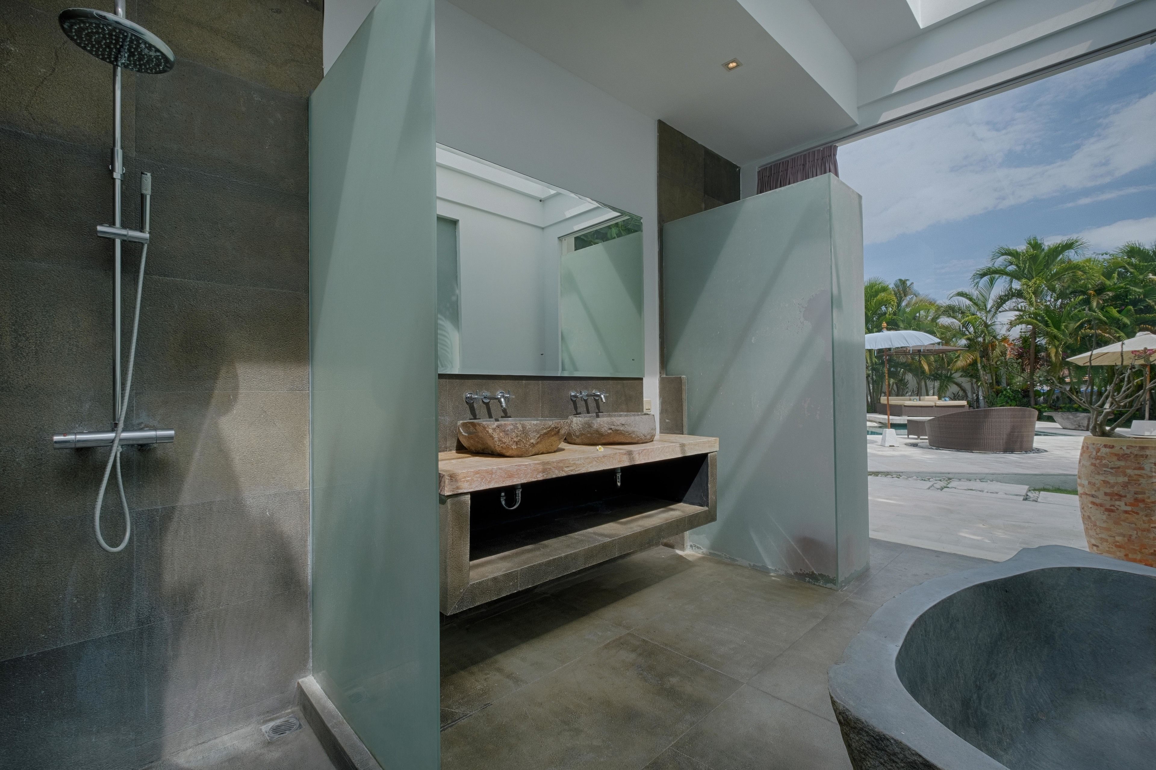 A modern bathroom with a freestanding bathtub, a glass-enclosed shower, and a vanity with a large mirror and two sinks.