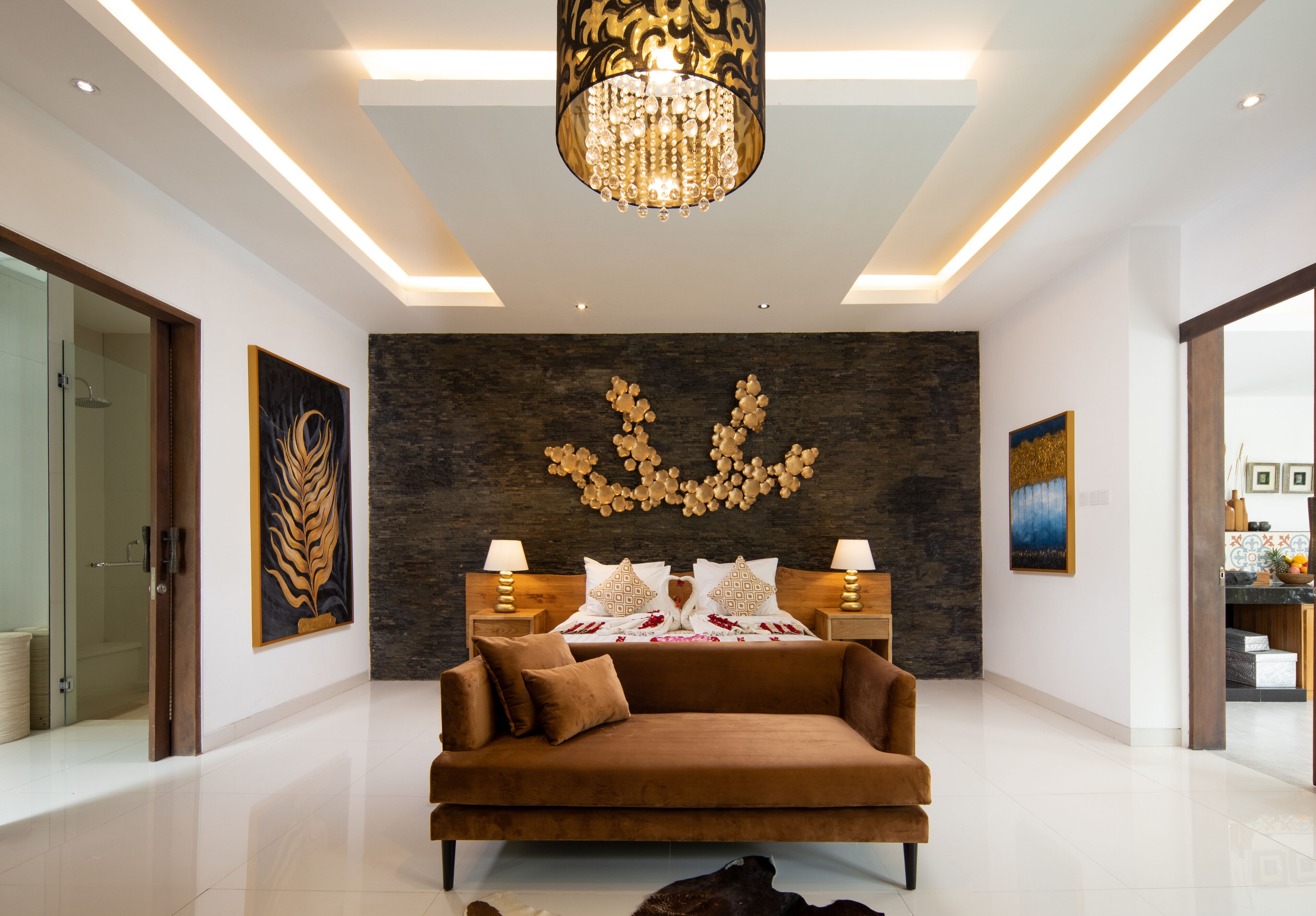 A modern bedroom with a large bed, a chandelier, and artwork on the walls.
