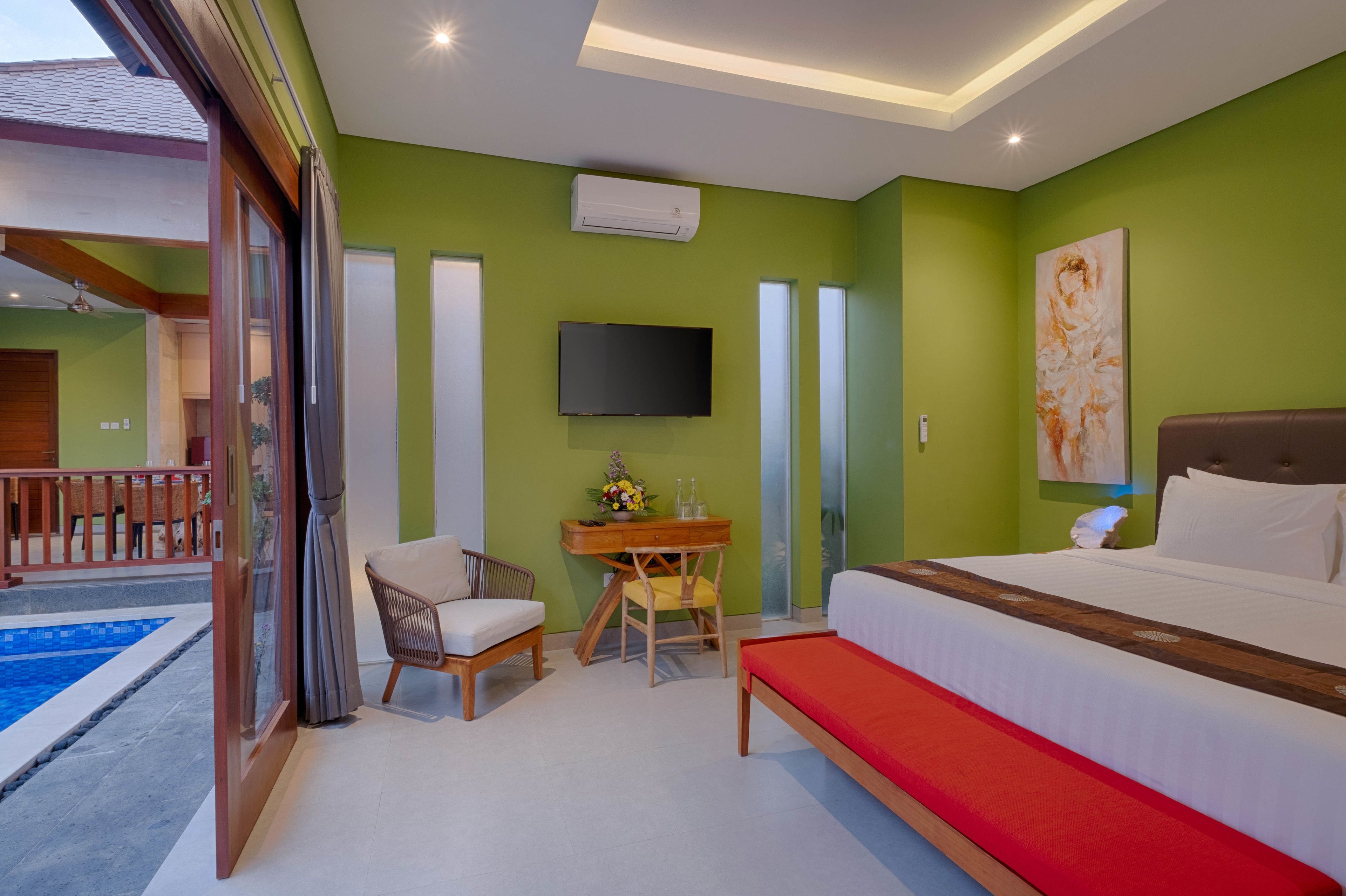 A hotel room with a bed, a desk with a chair, a television, and a painting on the wall.
