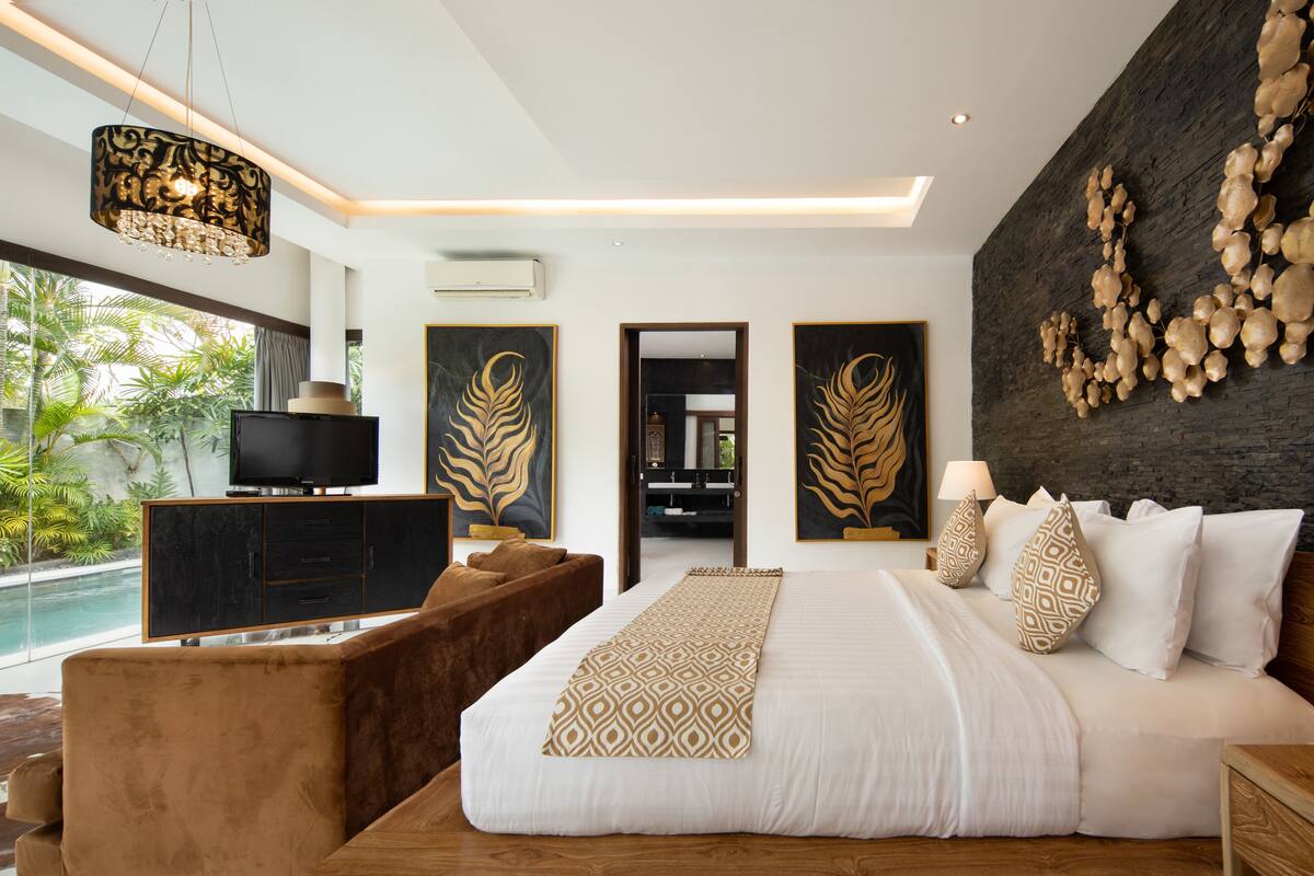 Een moderne slaapkamer met een groot bed, een televisie, een houten nachtkastje en uitzicht op een zwembad.