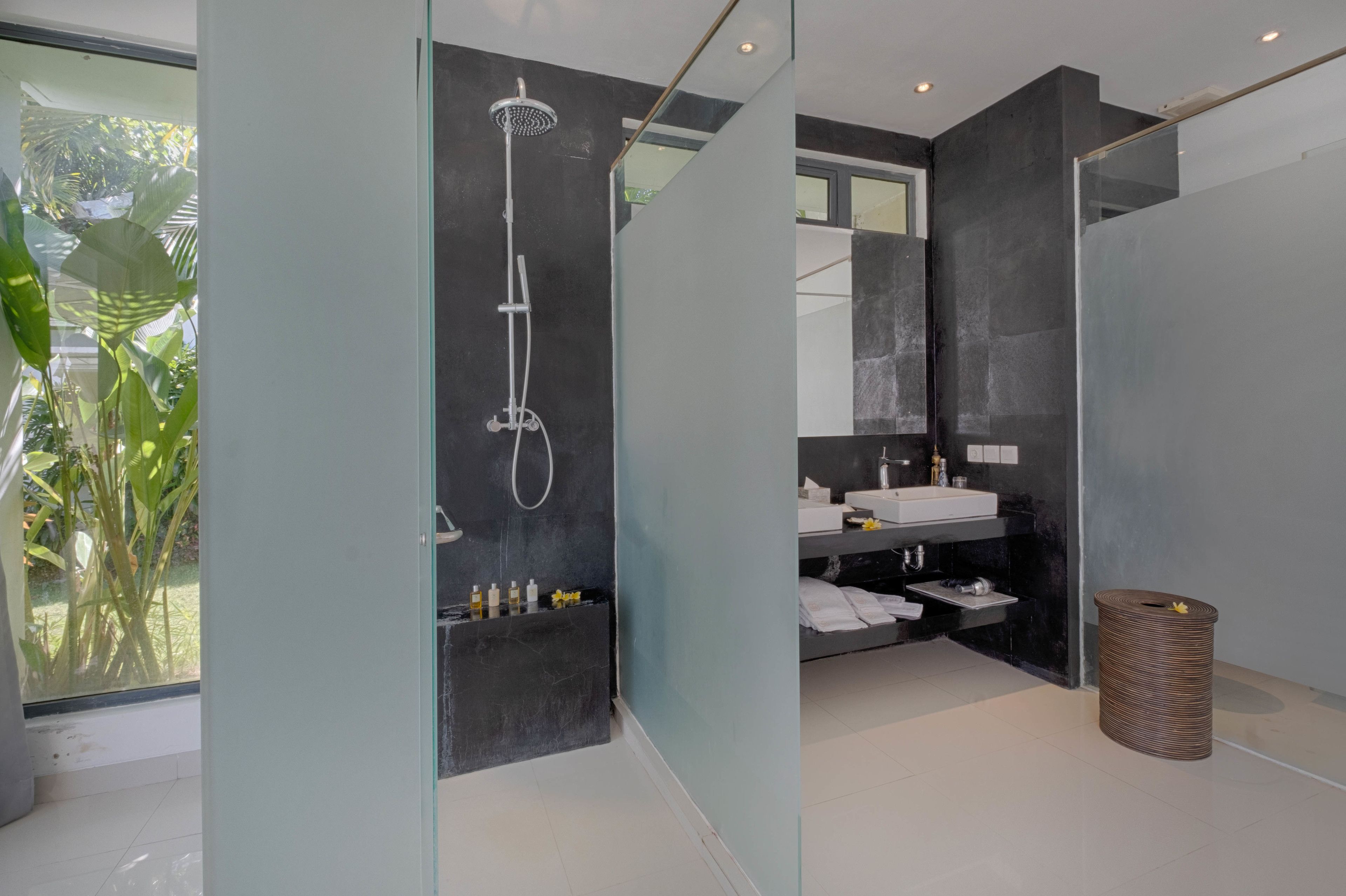 Een moderne badkamer met een douchecabine van glas, een wastafel en een spiegel.