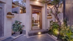 A well-lit entrance with a decorative archway, potted plants, and a pathway leading to the interior. - Canggu Villa by Sanga Sanga Hospitality (Canggu)