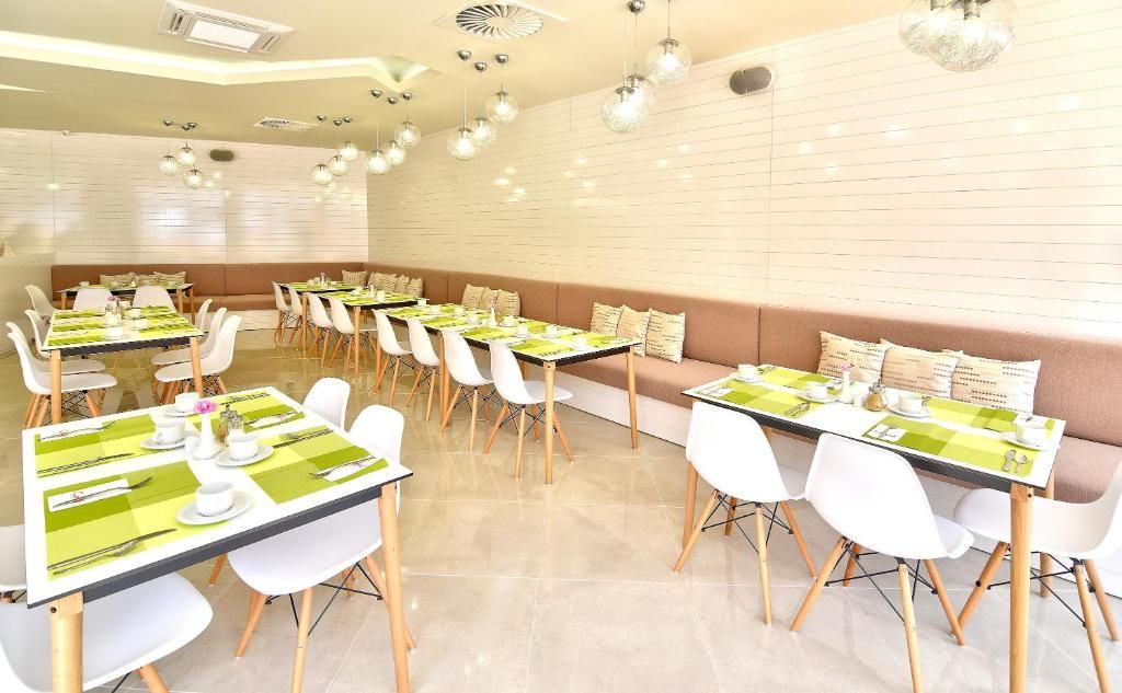 A dining area with multiple tables set for meals, white chairs, and a long bench.