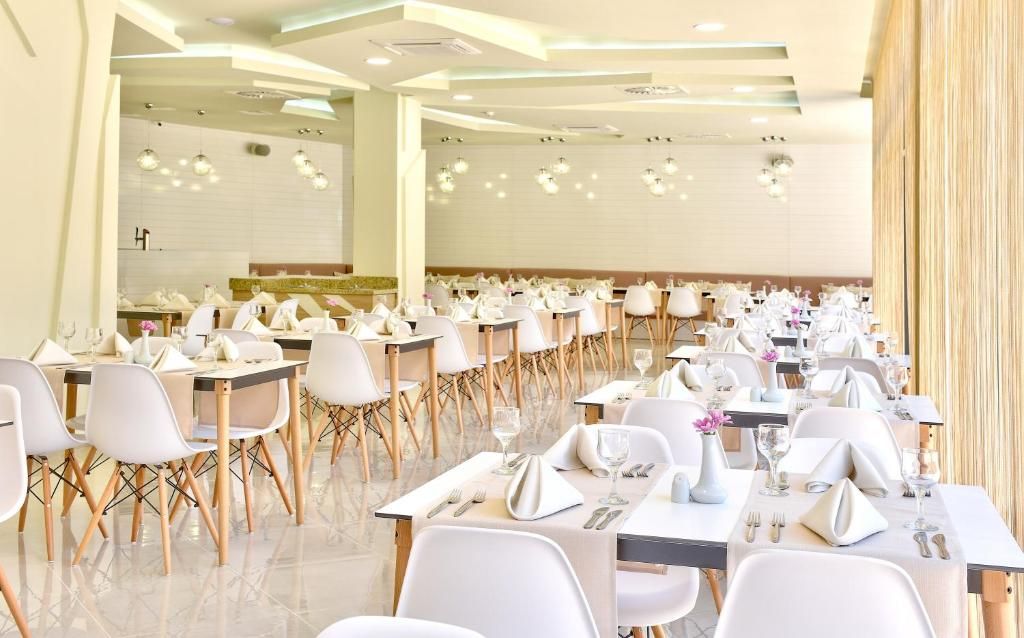 Un grand espace dédié à la salle à manger, avec de nombreuses tables et chaises disposées en rangées.