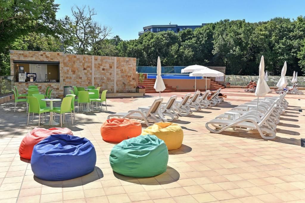 A poolside area with lounge chairs, bean bags, and a small bar area.