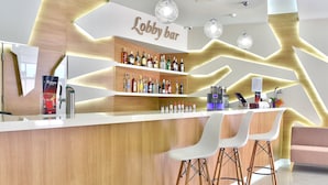 A lobby bar with a wooden counter, shelves of liquor bottles, and modern pendant lighting. - Hotel Grifid Foresta  Adults Only (Golden Sands)