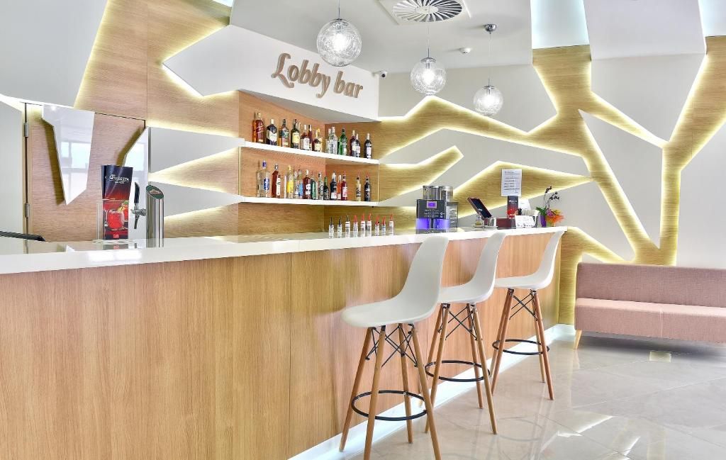 A lobby bar area with a wooden counter, white bar stools, and a sign that reads 'Lobby bar.'