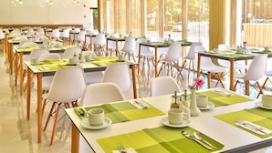 A dining area with multiple tables set for breakfast, each with white chairs, green placemats, and breakfast items. - Hotel Grifid Foresta  Adults Only (Golden Sands)