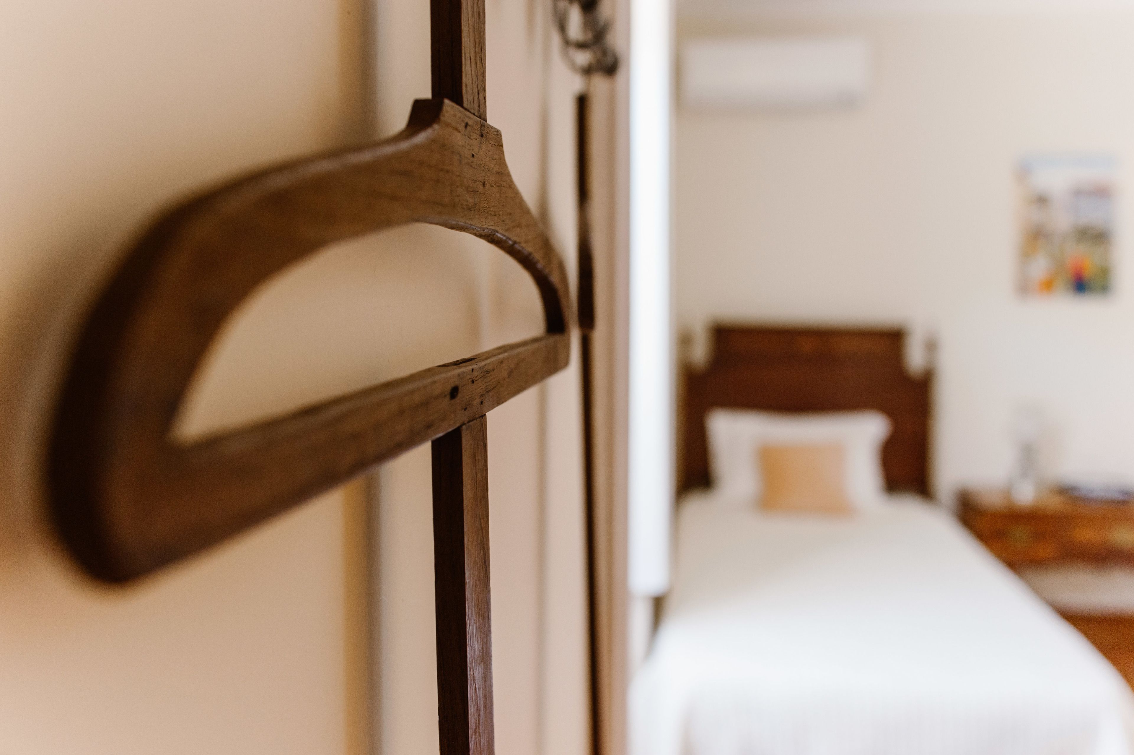 A wooden door handle and a bed with white bedding in a room.