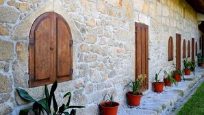 A stone building with arched wooden doors and potted plants along the side. - Casa Mindela Farmhouse (Vila do Conde)