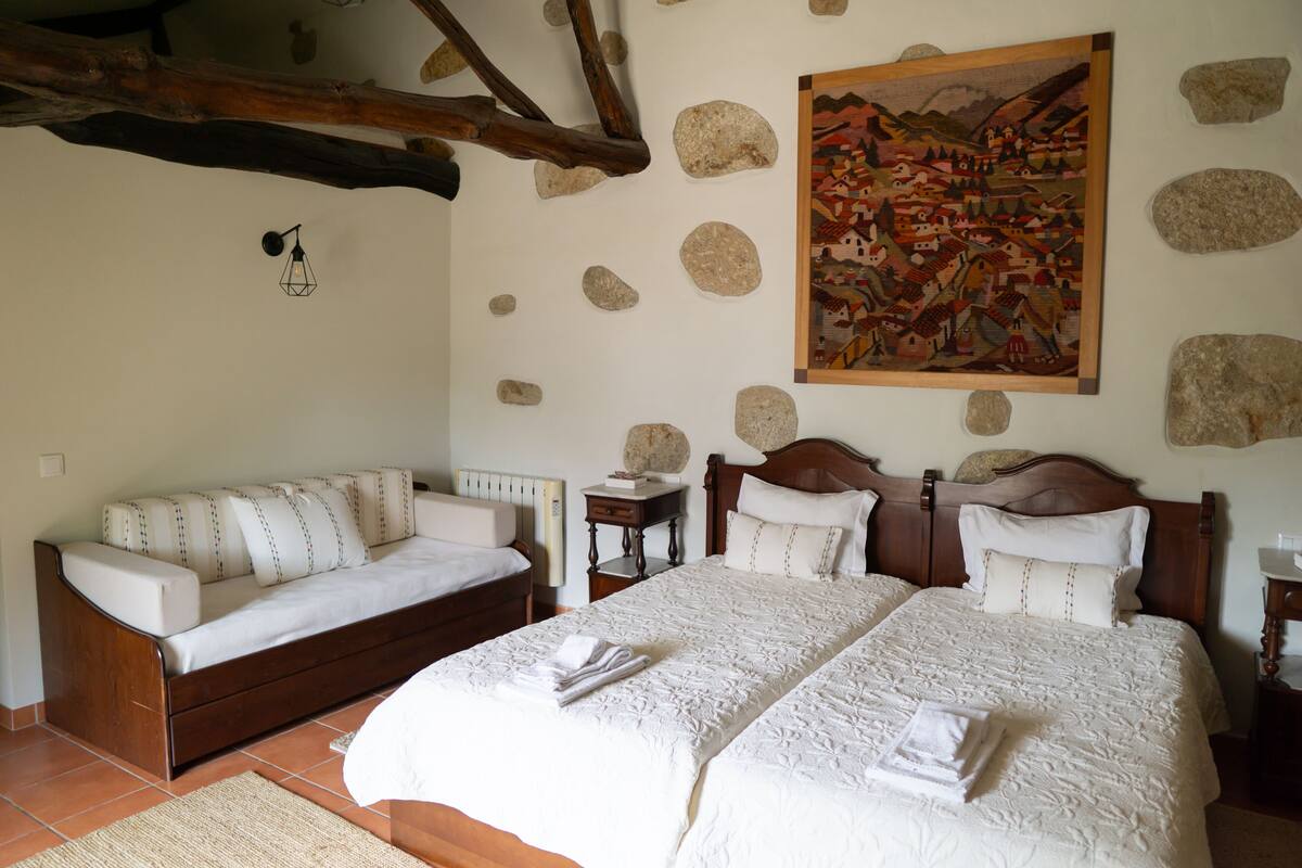 A bedroom with two beds, a sofa, a painting, and stone decorations.
