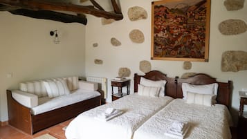 A bedroom with two beds, a sofa, a painting, and stone decorations.