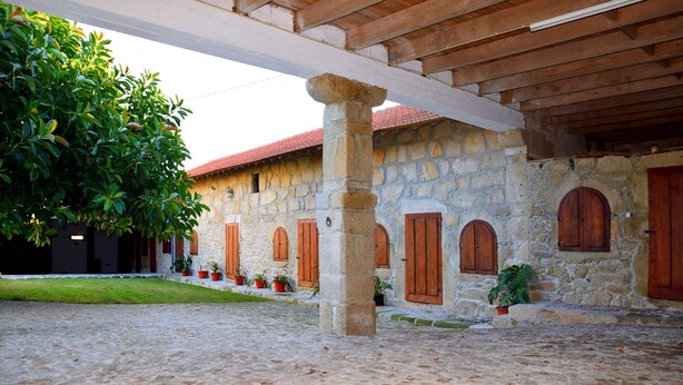 A courtyard with stone walls, wooden beams, and potted plants. - Casa Mindela Farmhouse (Vila do Conde)