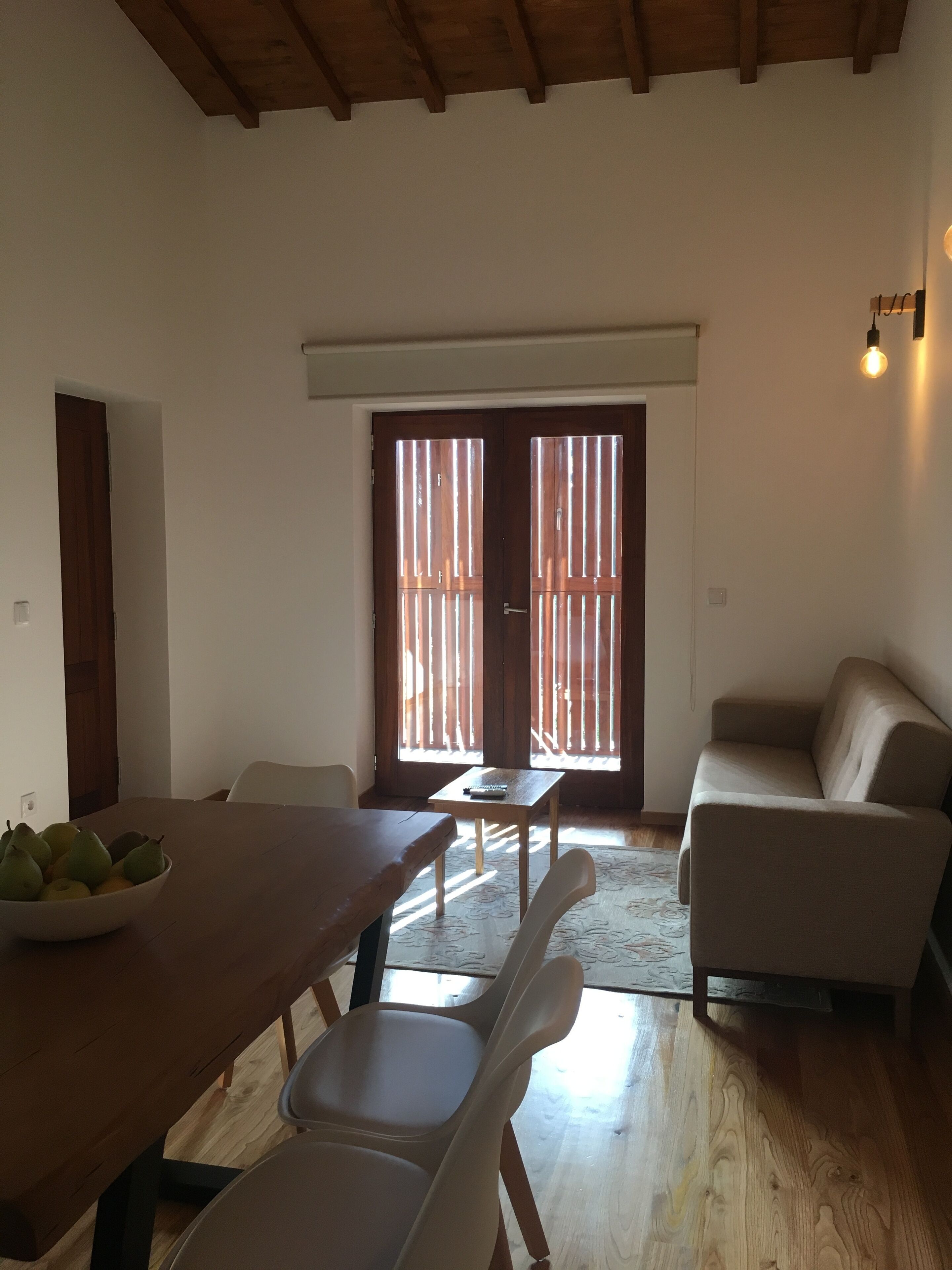 Ein Wohnzimmer mit Holztisch, einer Couch und einem Essbereich mit Stühlen.