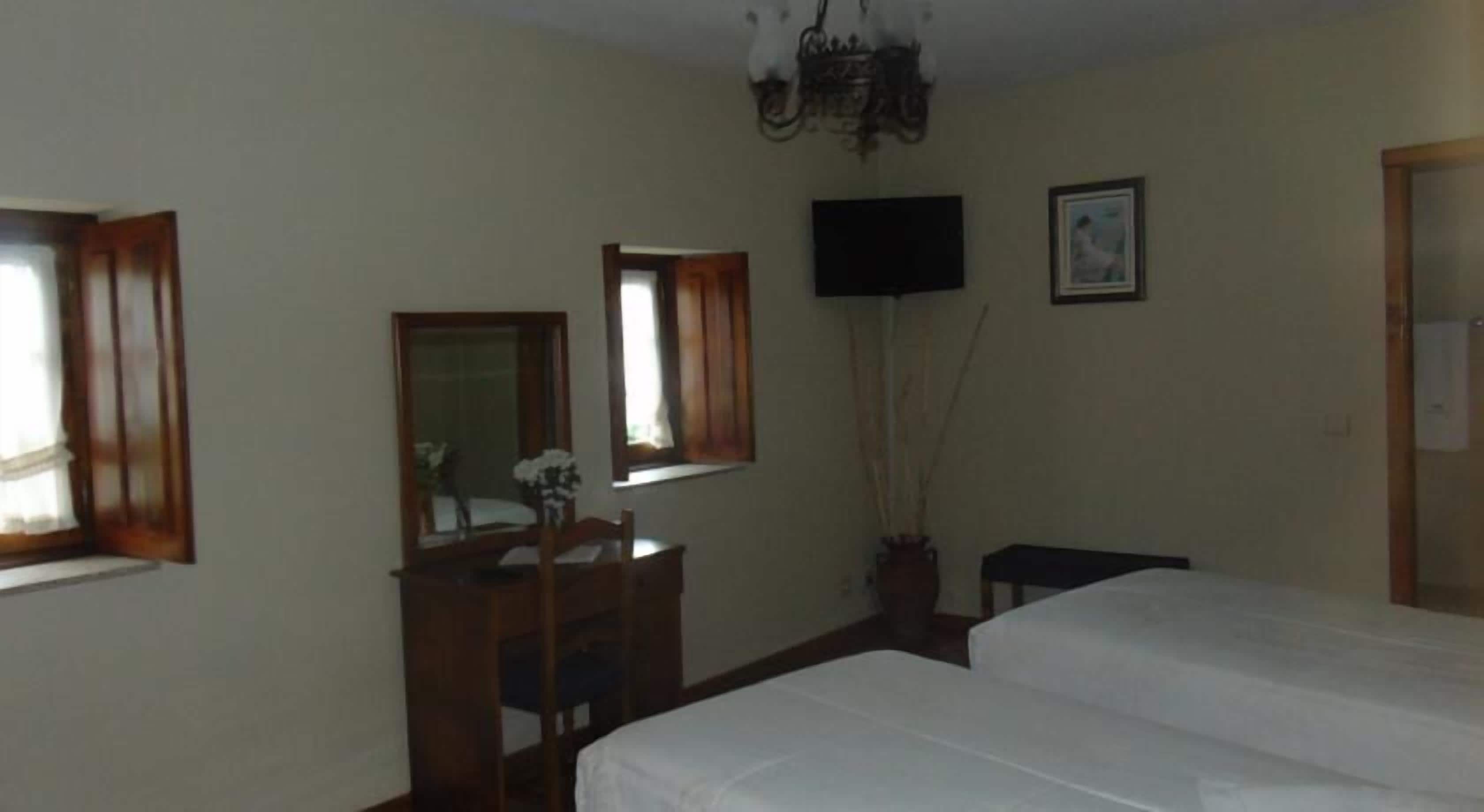 Un dormitorio con dos camas, un aparador, un espejo, un televisor y una ventana con cortinas.