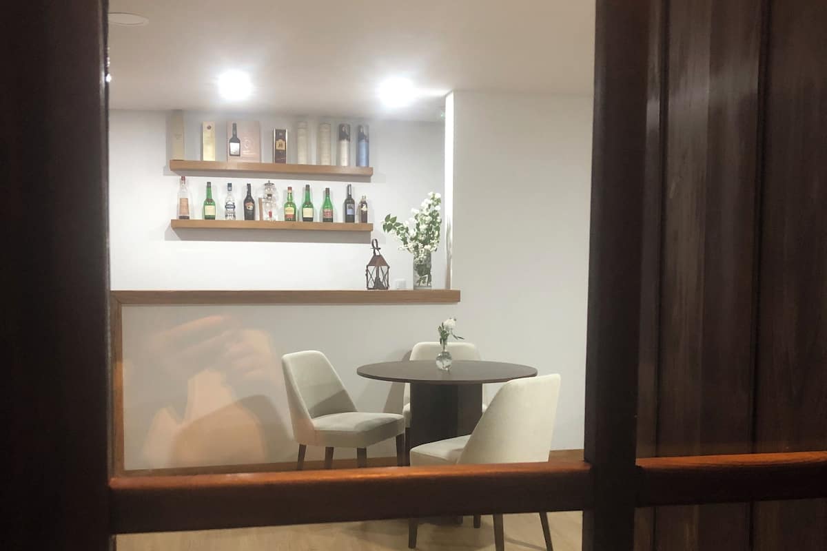Ein Essbereich mit rundem Tisch, vier Stühlen, Holzboden und Regalen mit Flaschen und einer Laterne.