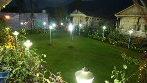 A well-maintained garden with a lawn, decorative lights, and a building in the background. - Aziz Palace (Srinagar)