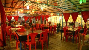 An indoor dining area with tables and chairs, a wooden floor, and a ceiling with lights. - Aziz Palace (Srinagar)