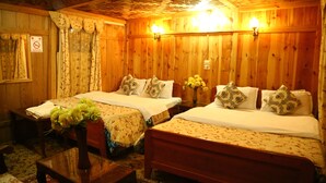 A wooden room with two beds, a small table, and a bench. - Aziz Palace (Srinagar)