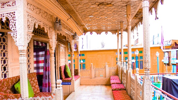 An ornate room with intricate carvings, a patterned floor, and a view of the outside. - Aziz Palace (Srinagar)