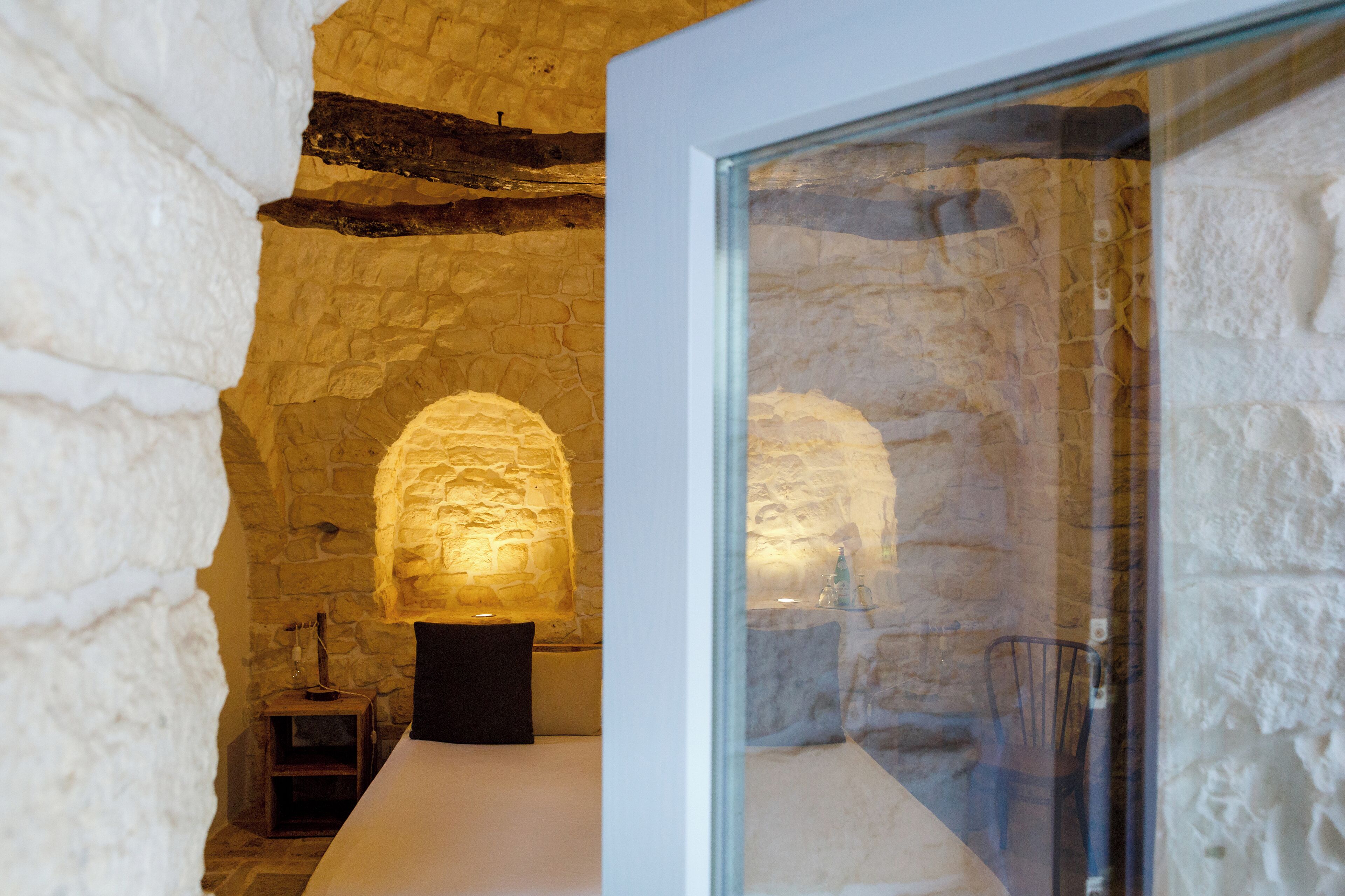 A stone-walled room with a bed and a table.