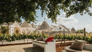 Un vignoble avec des bâtiments en pierre blanche et un espace de détente agrémenté de coussins.