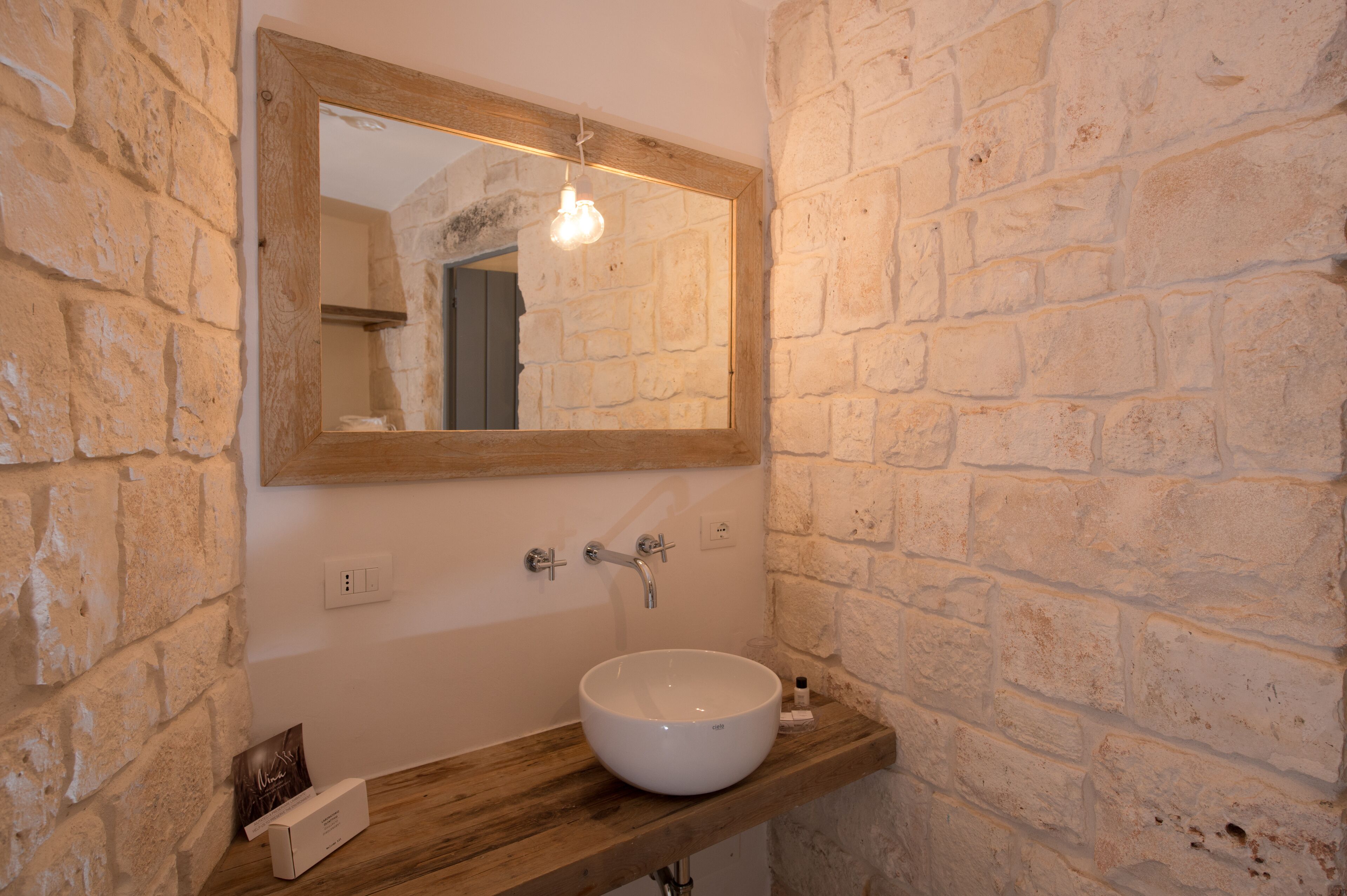 A bathroom with a wooden vanity, a white sink, and a mirror with a wooden frame.