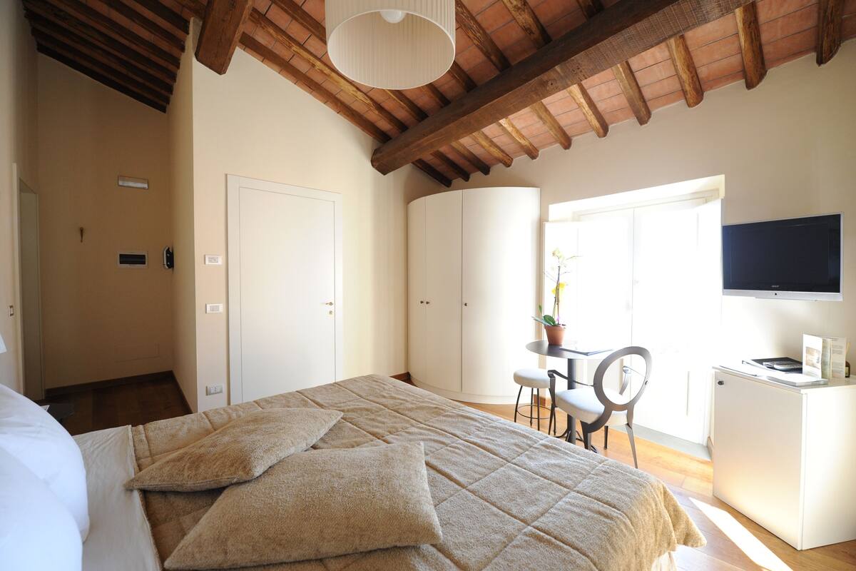 Un dormitorio con cama, escritorio, silla, televisor y armario.