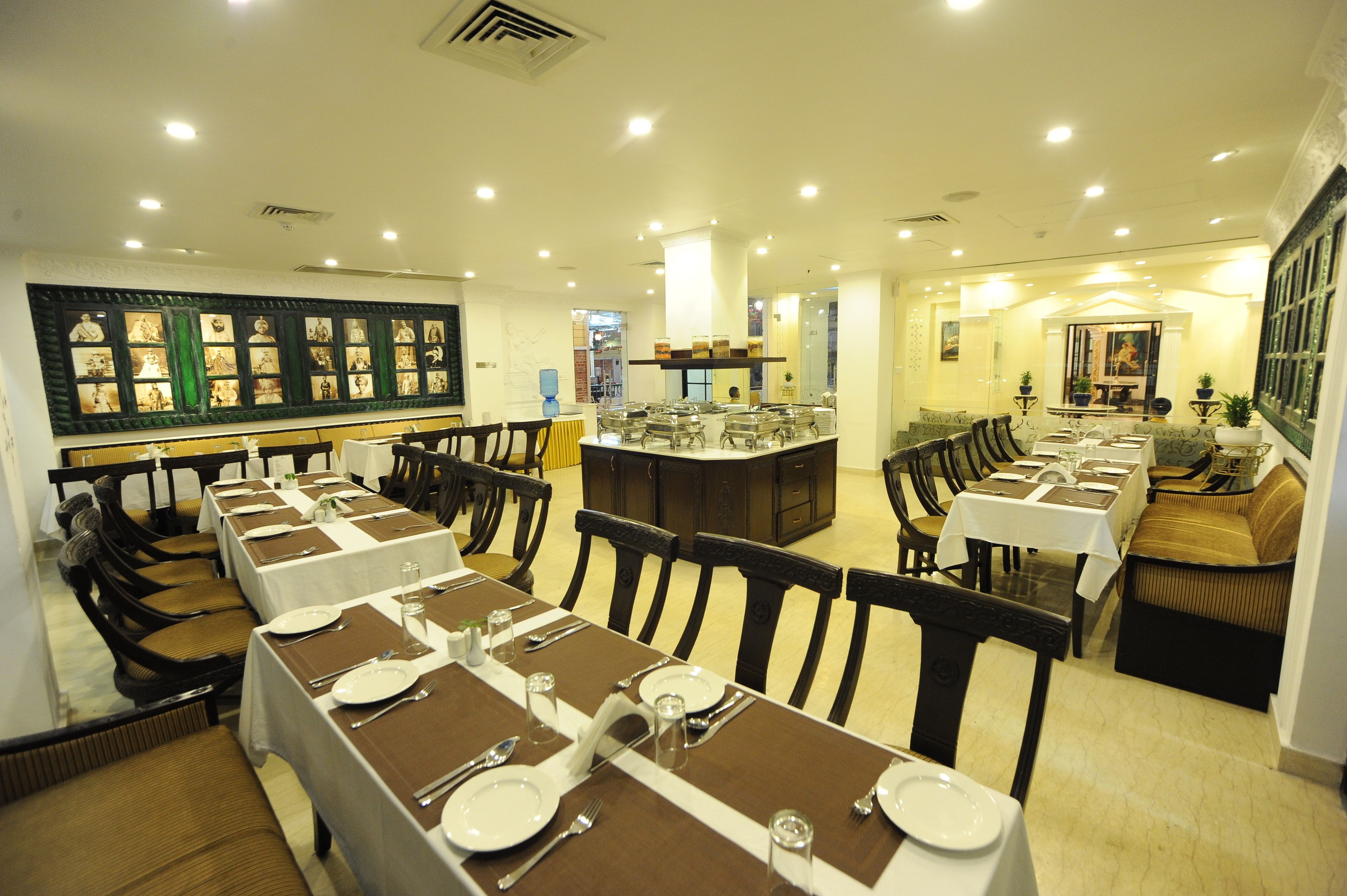 Un restaurante con varias mesas de comedor dispuestas con manteles blancos y posavasos marrones, rodeado de sillas de madera.