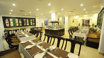 Un restaurante con varias mesas de comedor dispuestas con manteles blancos y posavasos marrones, rodeado de sillas de madera.