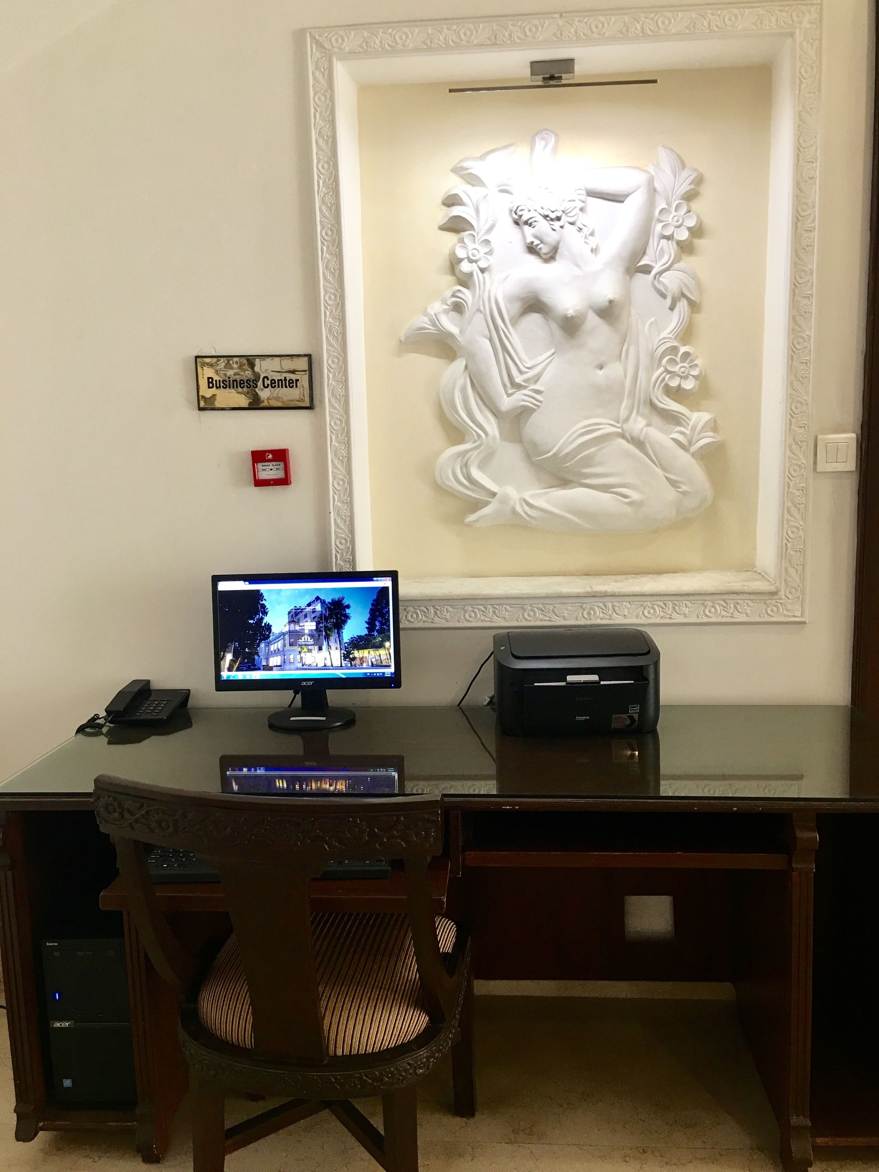 A business center desk with a computer, printer, and a framed artwork on the wall.