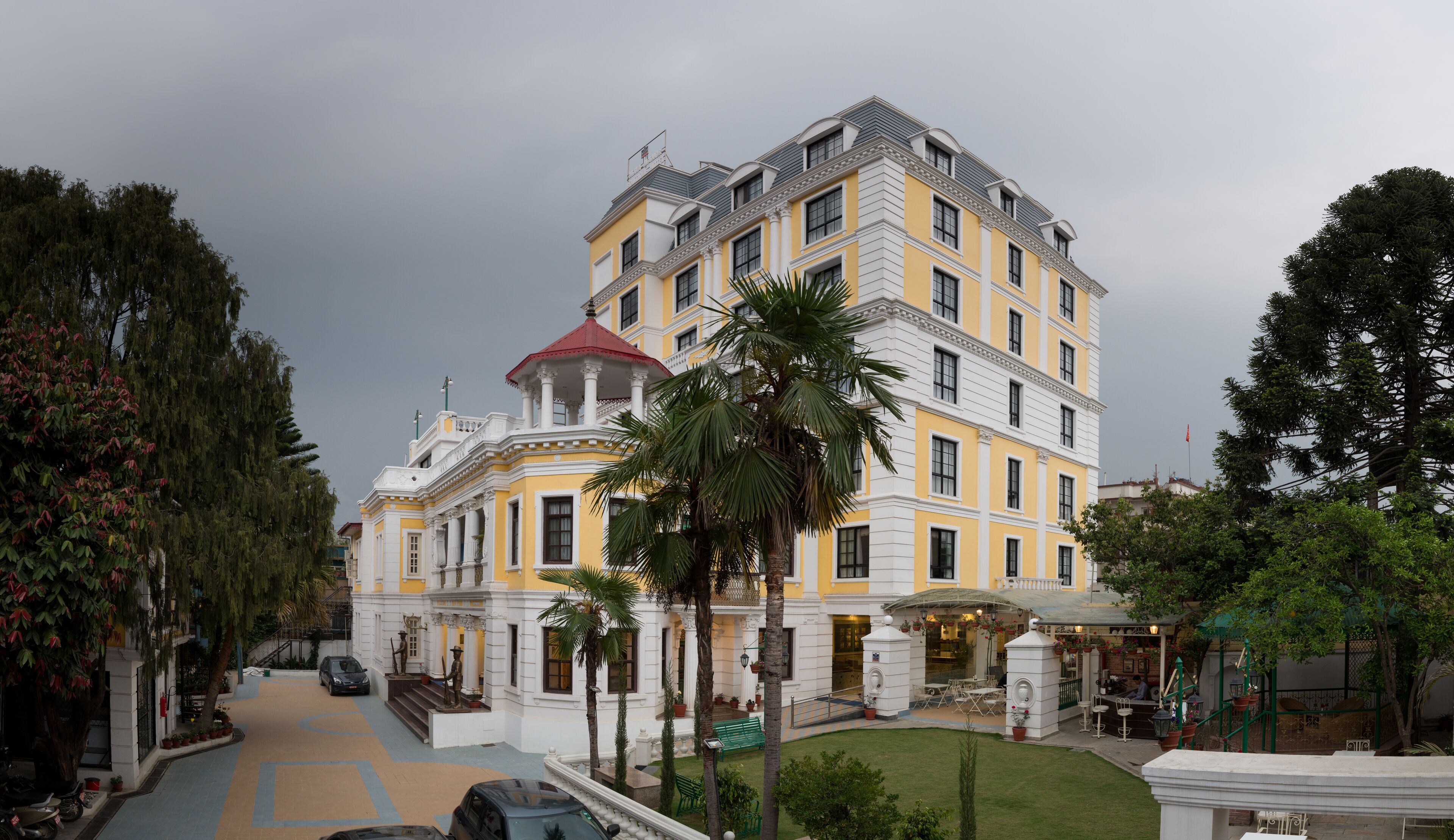A multi-story hotel with a yellow facade, white trim, and a red roof.