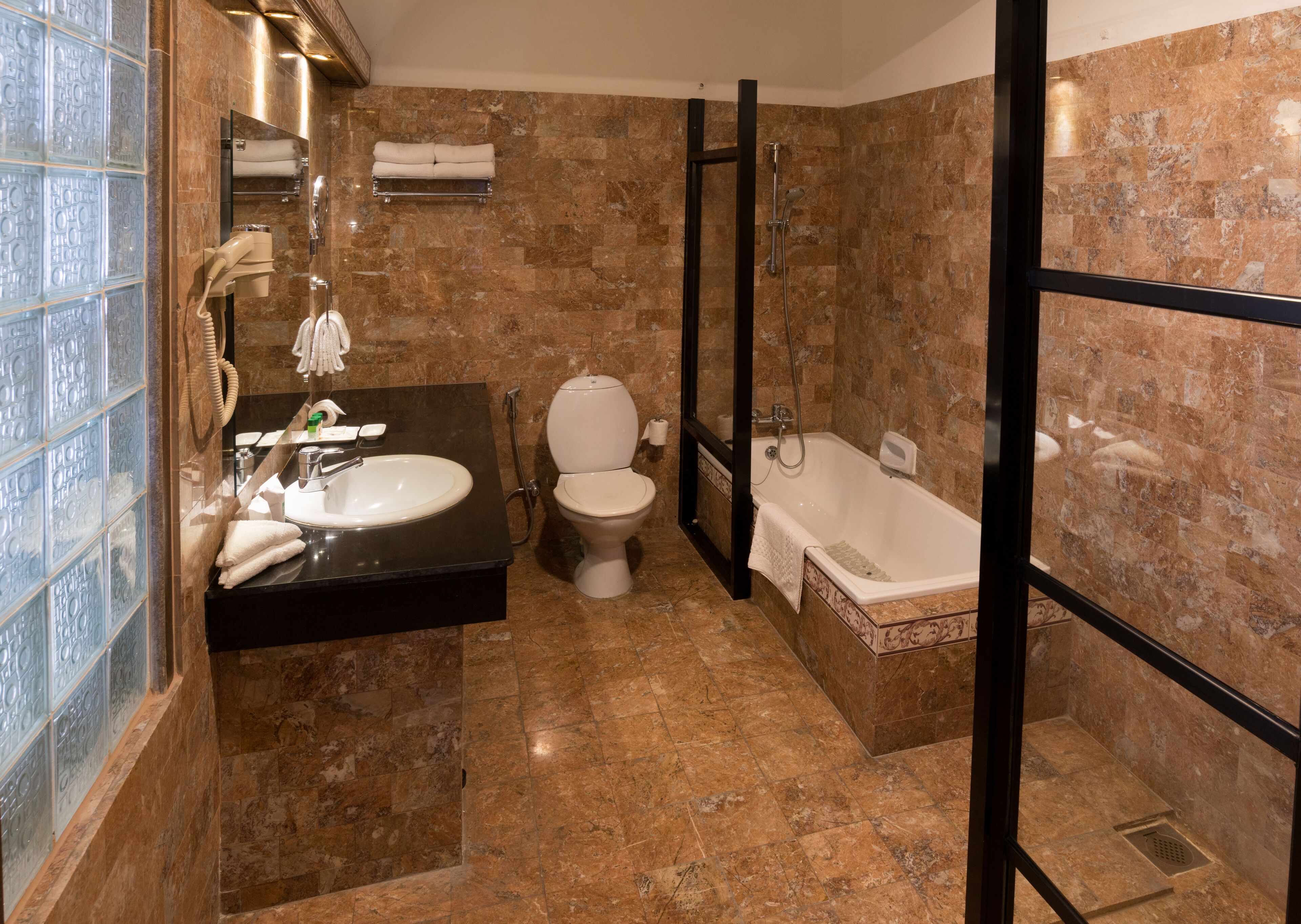 A bathroom with a marble floor, a sink, toilet, and a bathtub.