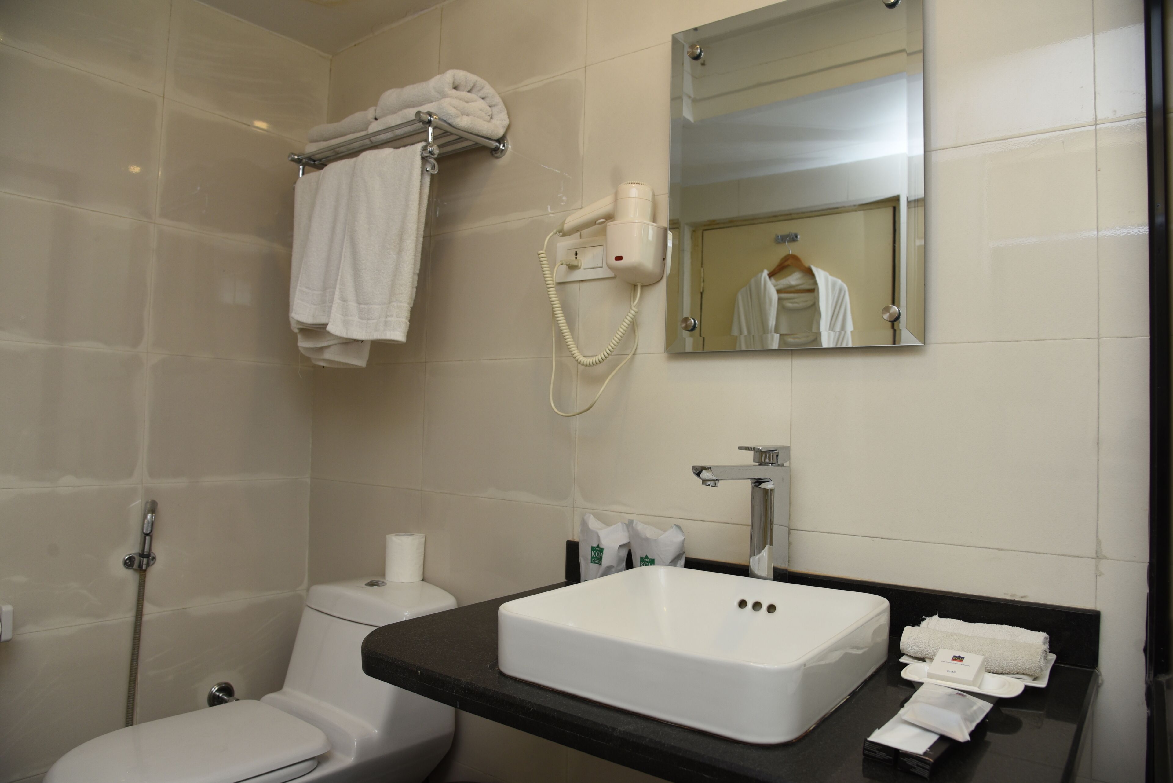 A bathroom with a white sink, a mirror, a towel rack, a hairdryer, and a toilet.