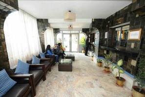 A lobby with seating, a reception desk, and potted plants. - Hotel Clarion (Lalitpur)