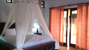 A bedroom with a four-poster bed, a nightstand with a lamp, and a view of the outside through an open door. - Bagus Homestay Pemuteran (Pemuteran)