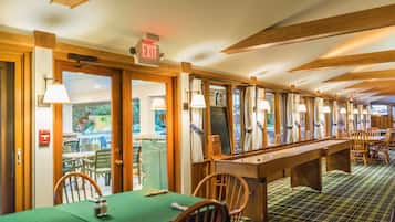 A restaurant with wooden beams, green tables, and chairs.