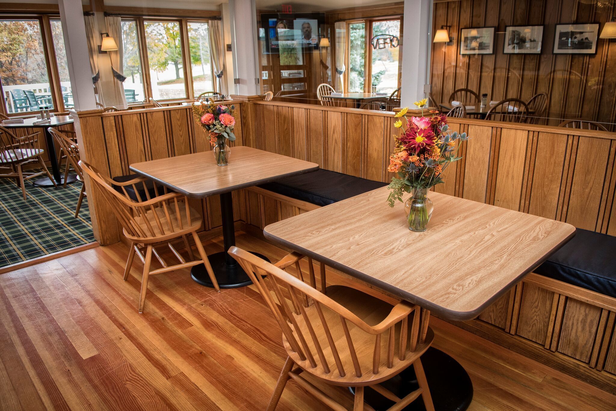 A restaurant interior with wooden booths, tables, and chairs.