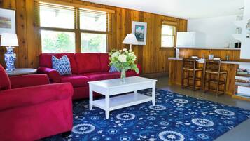 A living room with a red sofa, white coffee table, and a blue patterned rug.