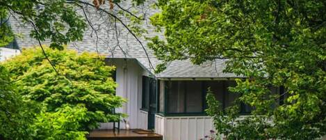 A house with a covered porch, a lawn, and a garden with various plants and flowers.