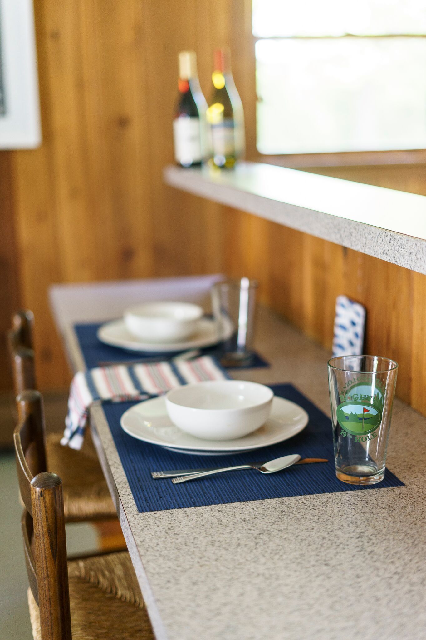Une table à manger dressée avec des assiettes, des bols, des couverts et un verre.