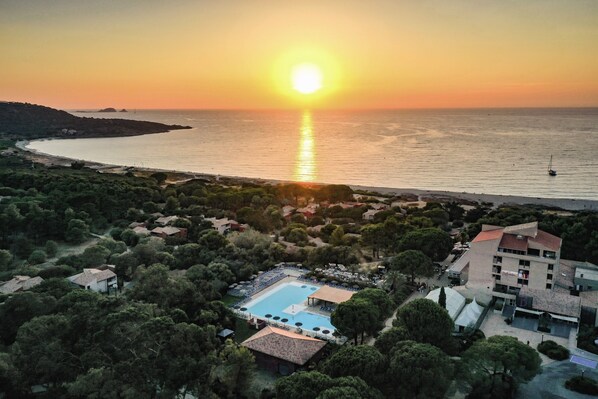 Un resort con piscina, acceso directo a la playa y vistas al atardecer.