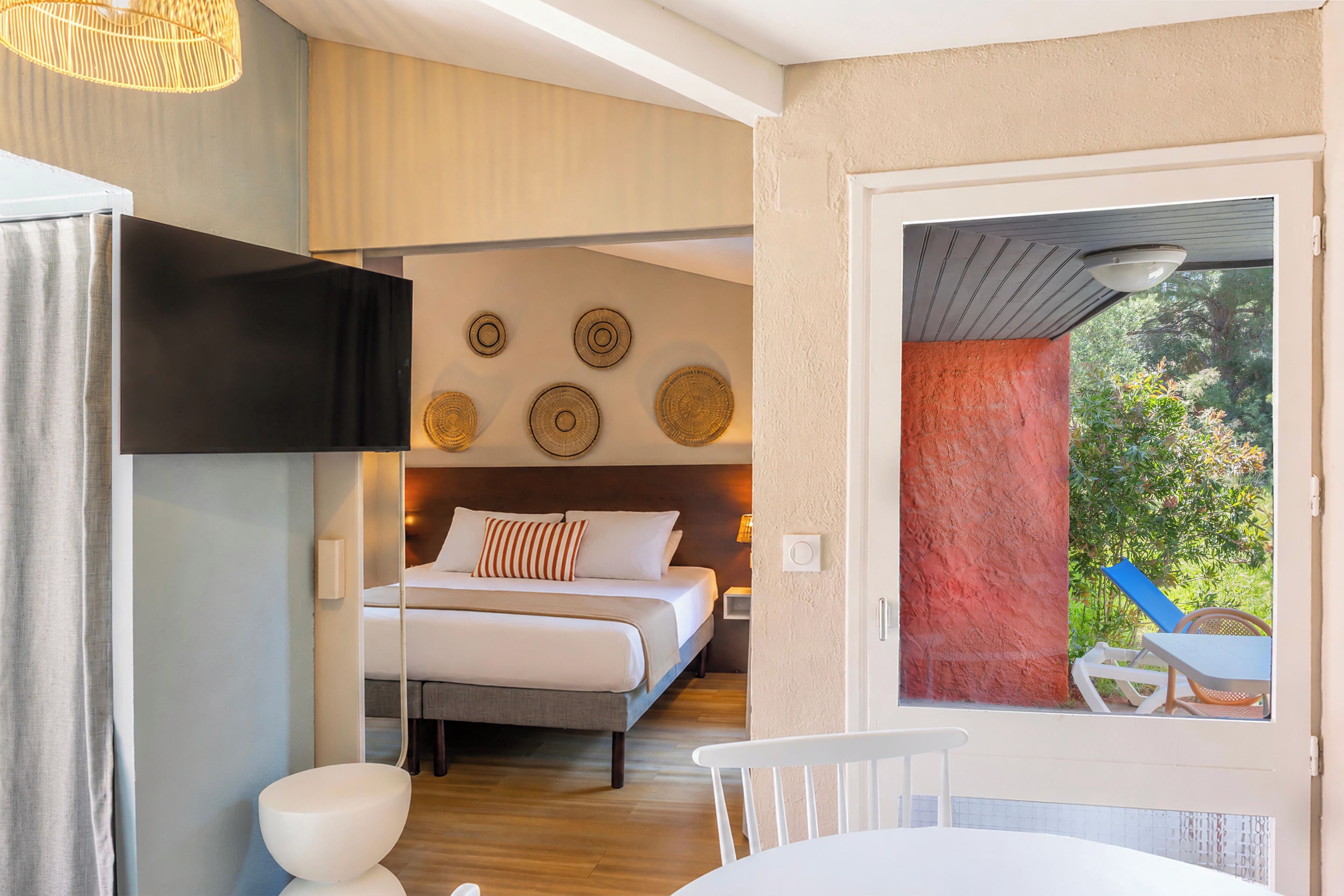 A bedroom with a bed, bedside table, and a view of the outdoors.