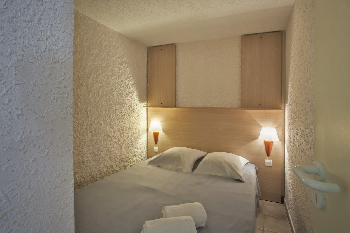 Ein Hotelzimmer mit einem Bett, zwei Wandleuchten und einem hölzernen Kopfteil.