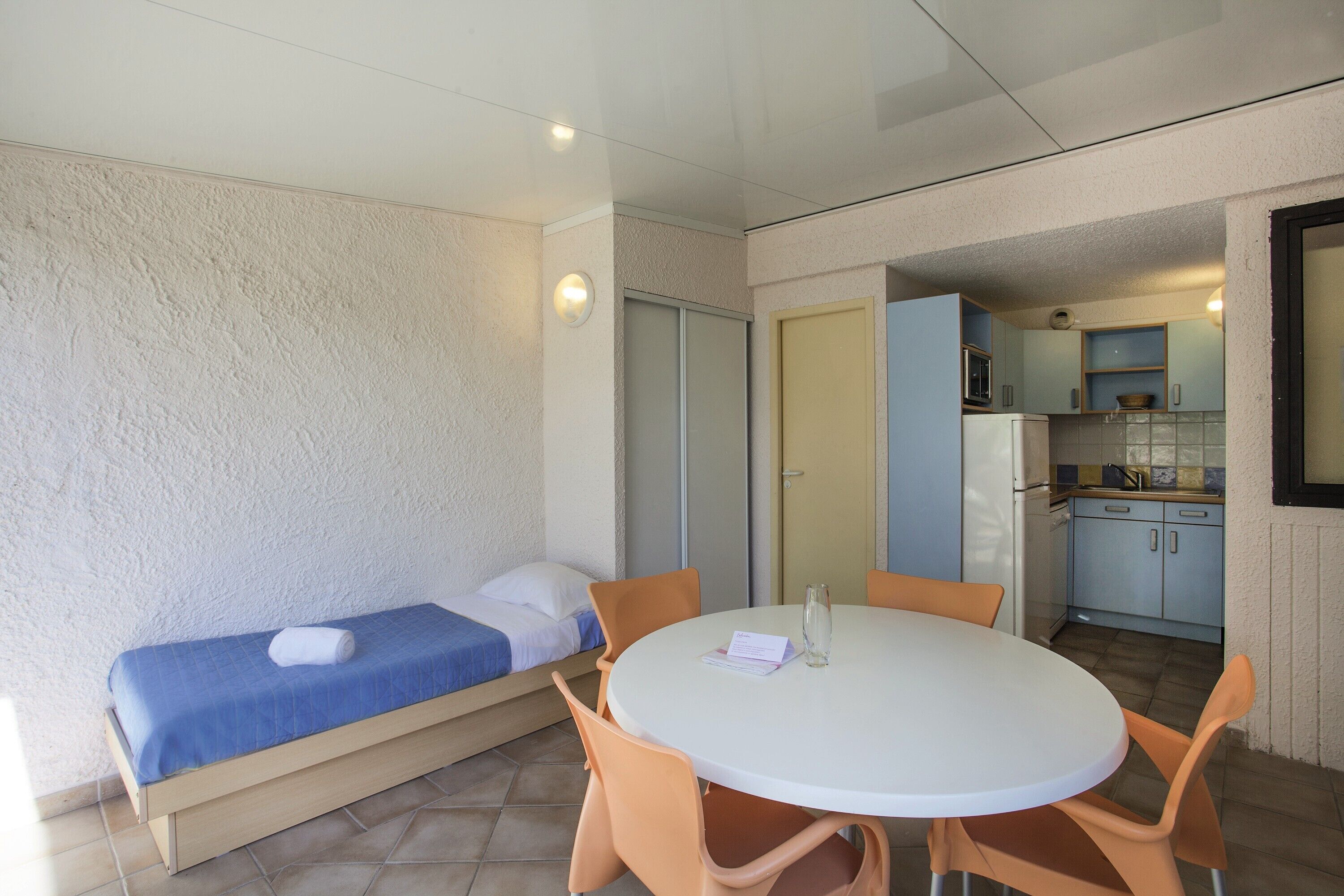 Une petite pièce comprenant un lit, une table ronde avec des chaises et un coin cuisine.